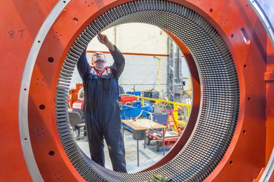 Engineer working inside a large motor stator during repair